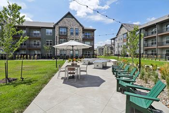 An outdoor patio with tables and chairs and an umbrella in front of an apartment building